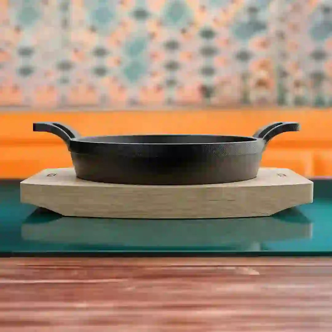 Roca Atlas 11cm cast iron braiser with two handles resting on a light-colored wooden tray.