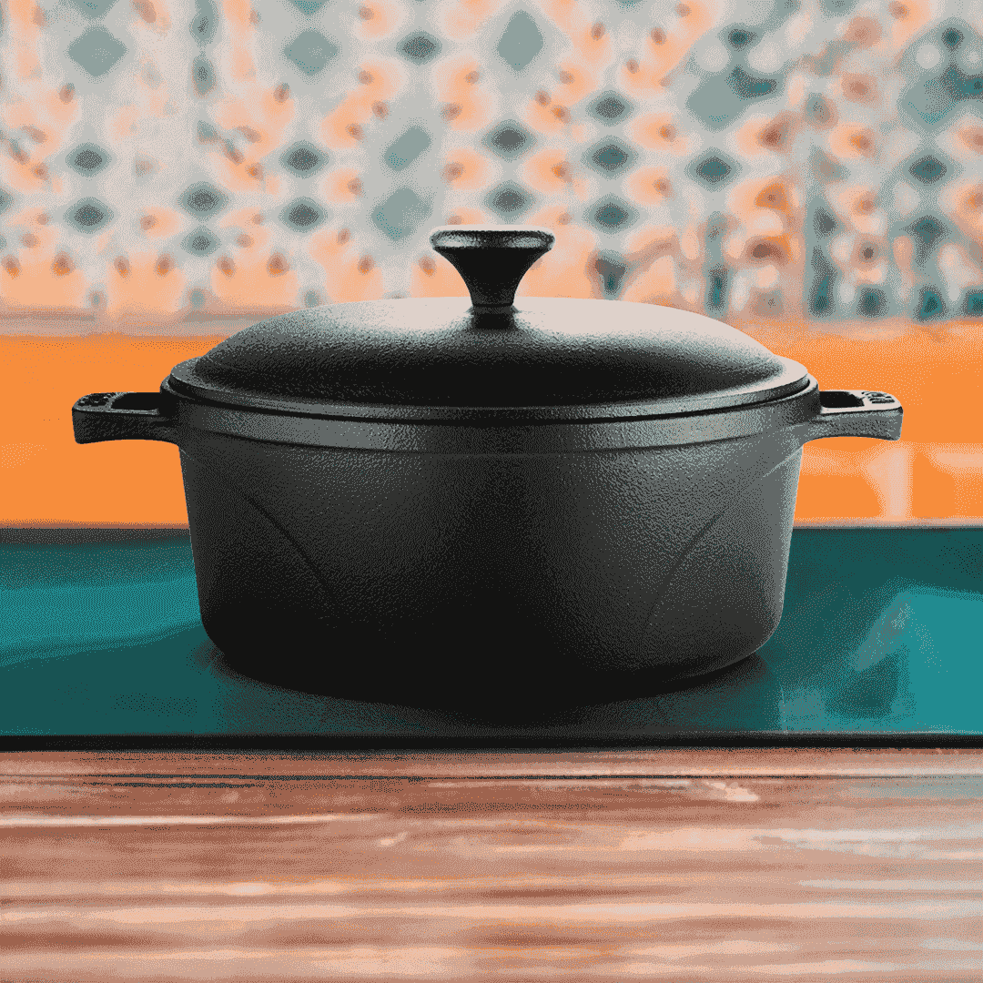 Black 24cm Roca Europa cast iron Dutch oven with lid on a glass stovetop.