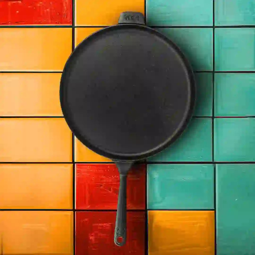 Roca Europa 28cm cast iron dosa tawa with handle on a colorful tiled background.
