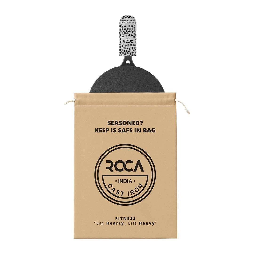 Roca Nix 30cm flat cast iron dosa tawa with a patterned handle sleeve and a tan storage bag.