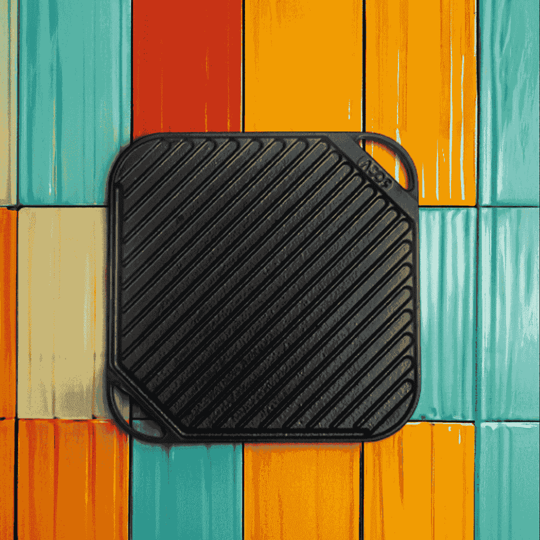 Square 25cm pre-seasoned black cast iron grill plate with diagonal ridges on a colorful background.