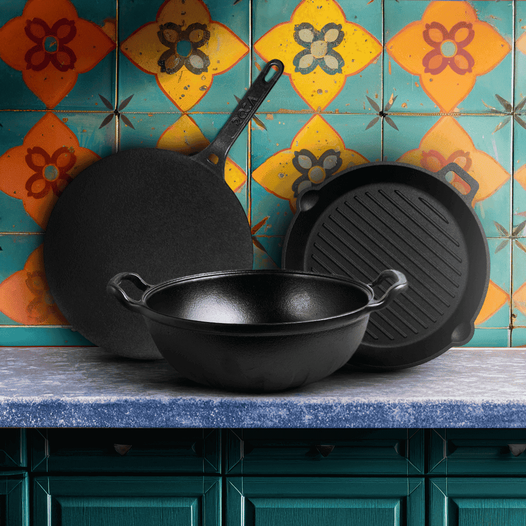 Set of black cast iron cookware on a kitchen counter with colorful tiles in the background