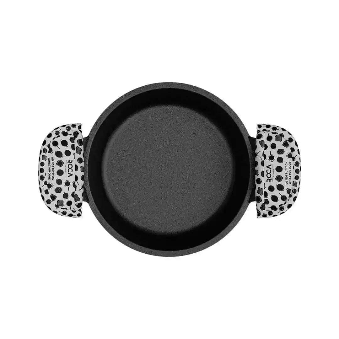 A top-down view of a round black non-stick pan with two handles featuring a black and white cow print pattern, on a solid white background.