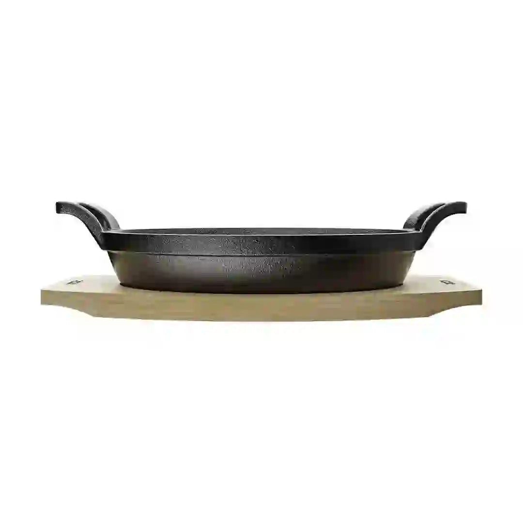 Roca Atlas 20.5 cm cast iron oval pan with two handles resting on a light-colored wooden tray.