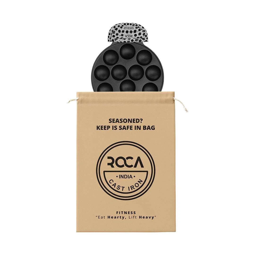 Roca Triton 12-pit cast iron paniyarakkal with a patterned handle sleeve and a cotton storage bag.