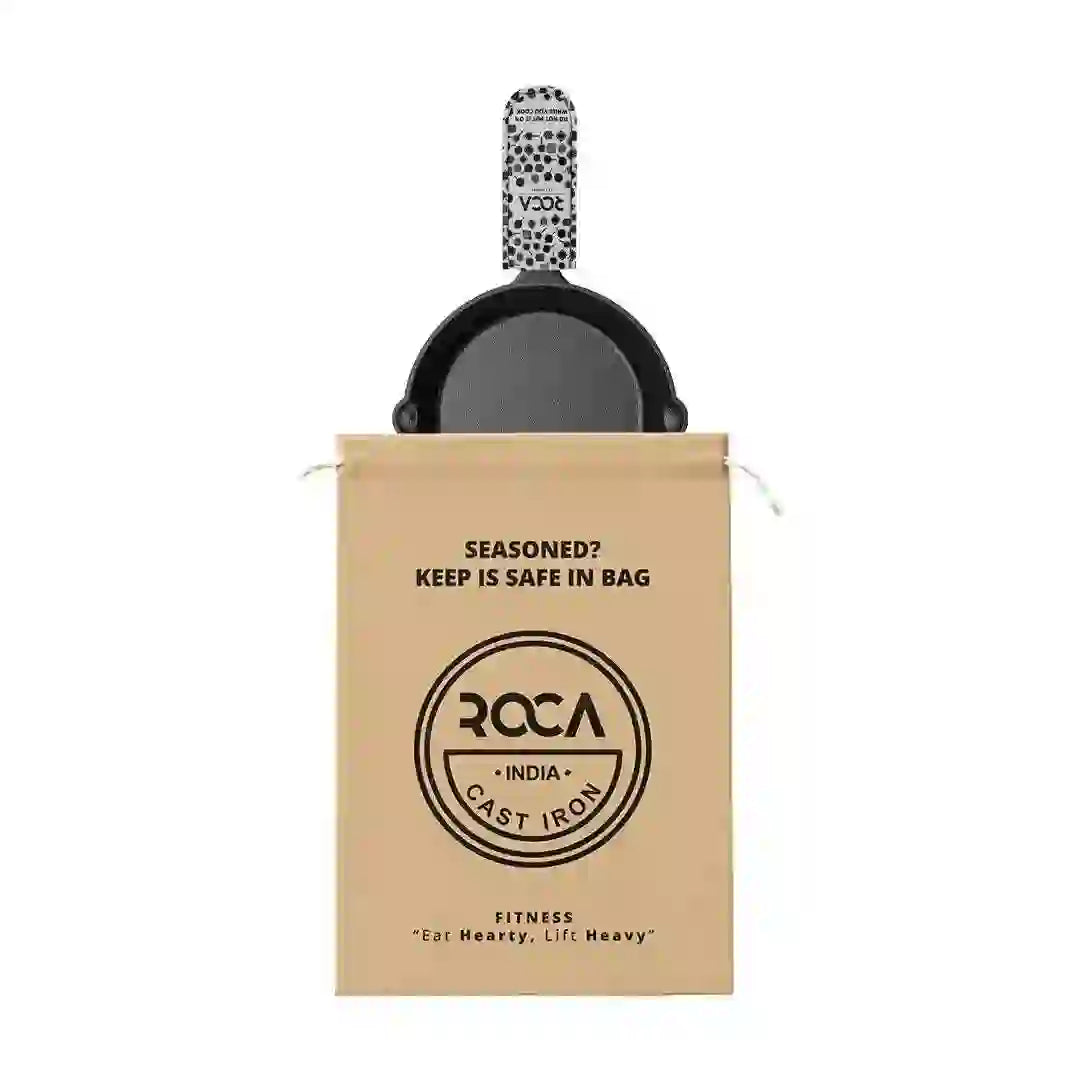 Roca 25cm cast iron skillet with a patterned handle sleeve and a branded tan storage bag.