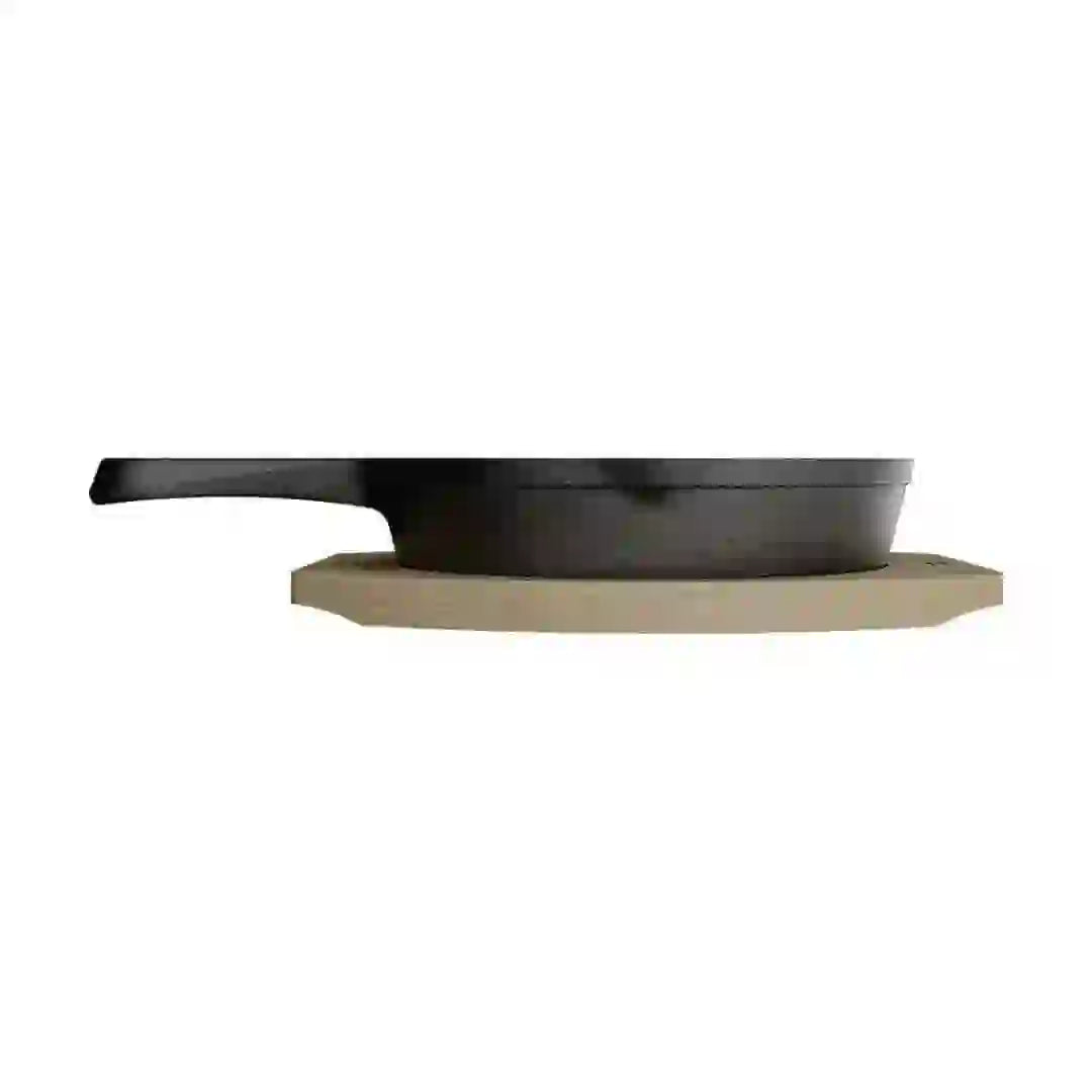 Side view of a small black cast iron grill pan resting on a light-colored wooden tray.