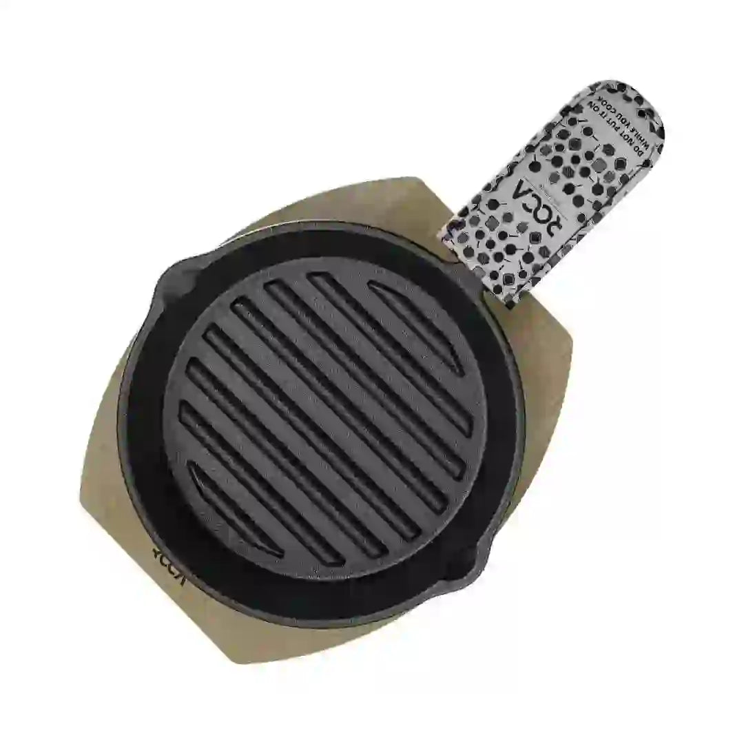 Roca Atlas 12.5cm cast iron grill pan on a wooden tray with a patterned cotton handle sleeve.