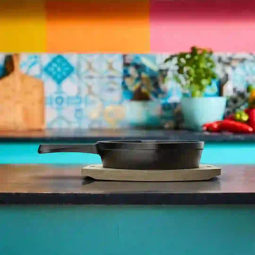Roca Atlas 12.5cm cast iron grill pan on a wooden tray in a colorful kitchen setting.