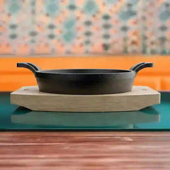 Roca Atlas 11cm cast iron braiser with two handles resting on a light-colored wooden tray.