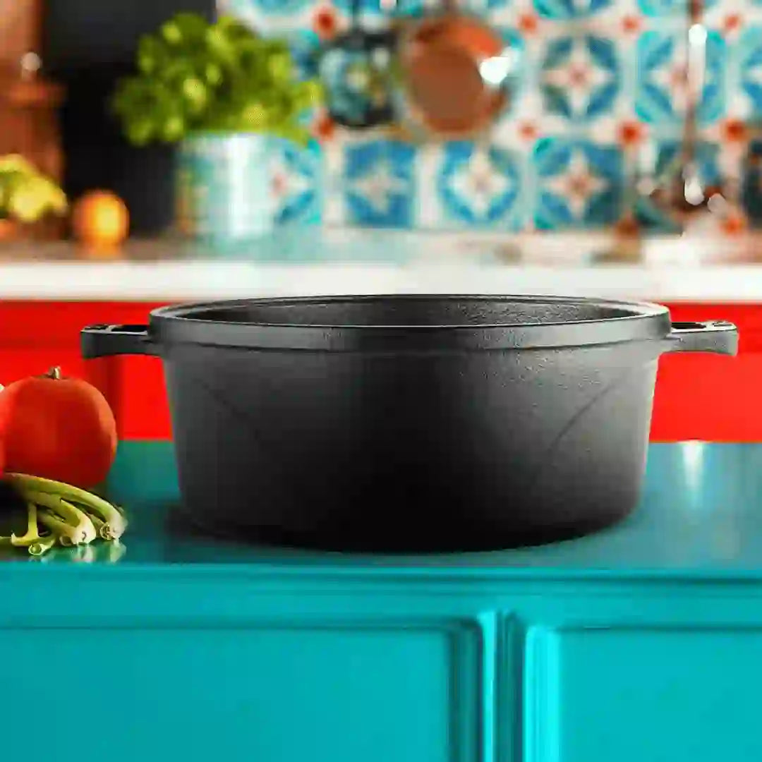 Roca Europa 24cm pre-seasoned black cast iron Dutch oven on a blue countertop.
