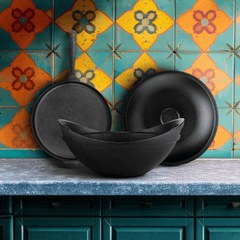Black ceramic bowls on a countertop with a colorful tiled wall in the background