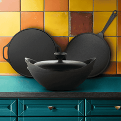Black cookware set on a teal countertop with a colorful tiled wall background