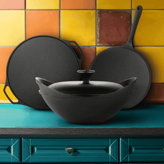 Black cast iron cookware set on a colorful tiled wall background