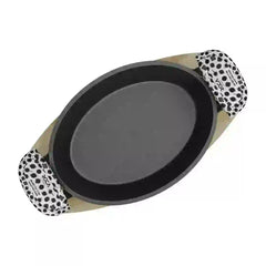 Roca Atlas cast iron oval pan on a wooden tray with patterned cotton handle sleeves.