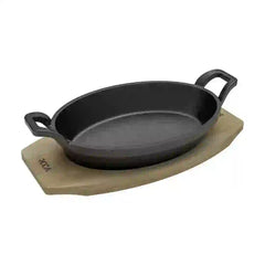 Roca Atlas 20.5 cm cast iron oval pan with two handles resting on a light-colored wooden tray.