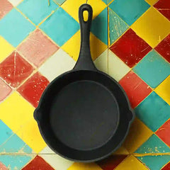 Roca Europa 19cm pre-seasoned black cast iron skillet on a colorful geometric tiled background.